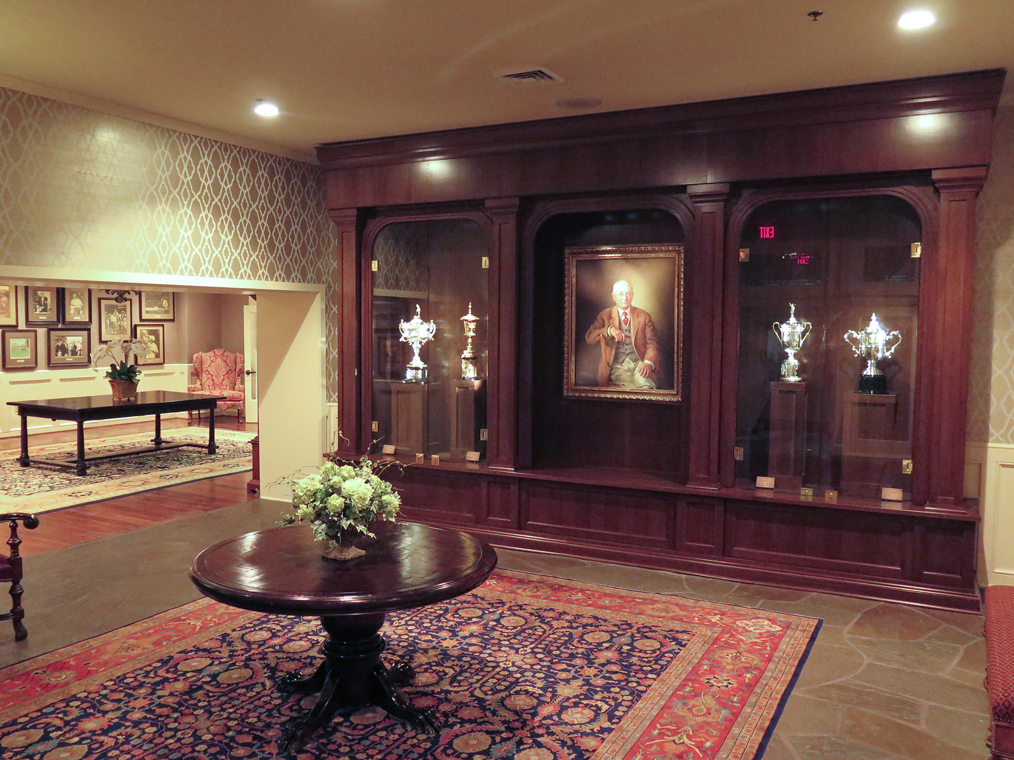 Traditional styled room with round center table, Wooden display cases against back wall with artifacts and spotlighting throughout