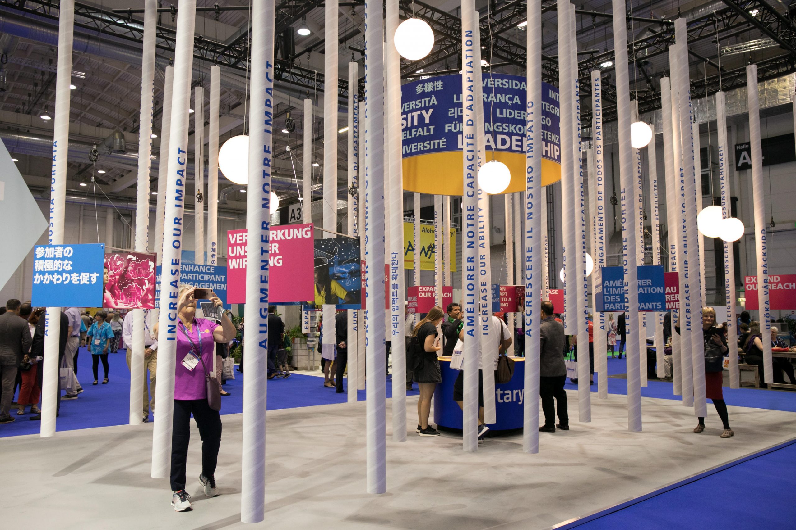 Large vertical poles with words signifying Rptary's impact and mission, people taking pictures among the display area