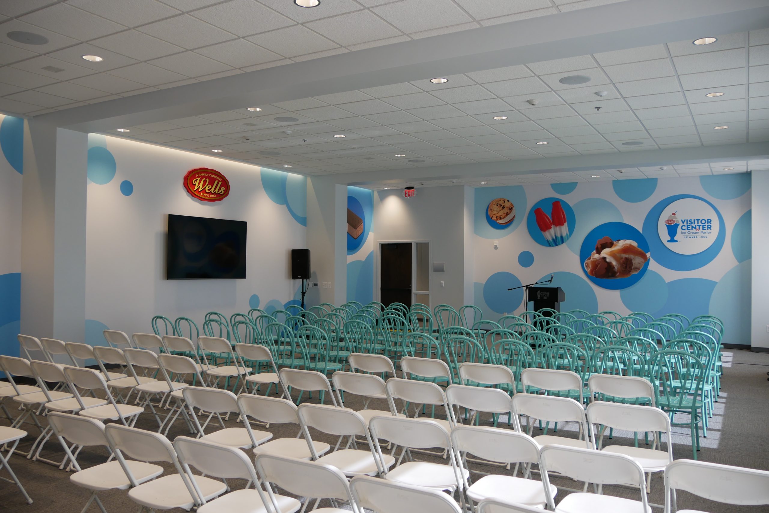 Lareg event space with seating, a podium wall monitors and wall graphics