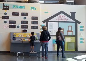 Visitors viewing wall graphic that describes how corn is turned into ethanol and how it's used in the home